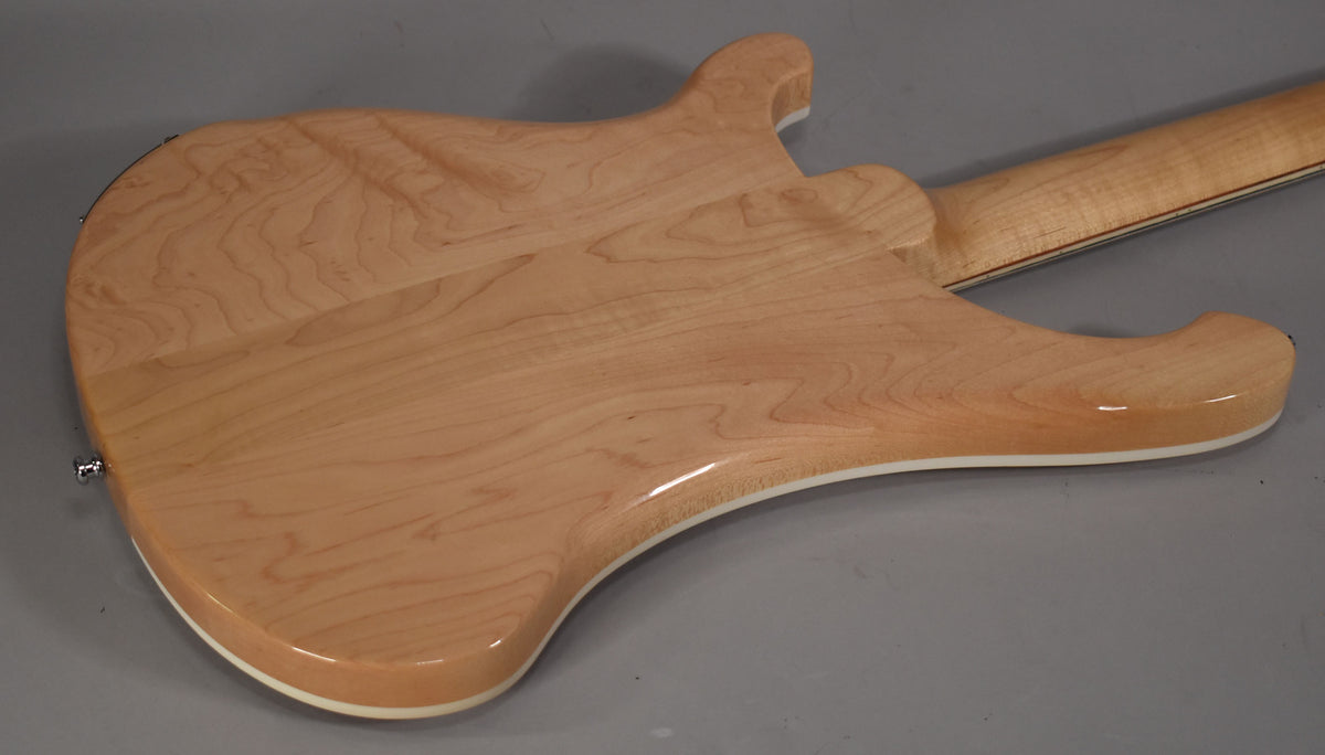The back of the natural maple bass body and neck, showing the light wood grain and glossy finish with white binding.