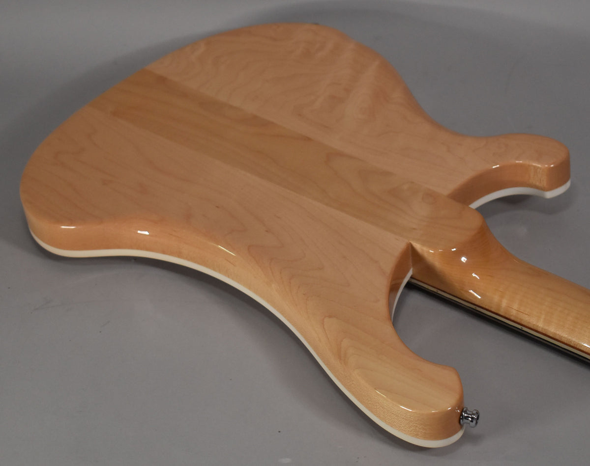 The bass's glossy natural wood body, with white binding, is viewed from the back, showing the neck joint and a chrome strap button.