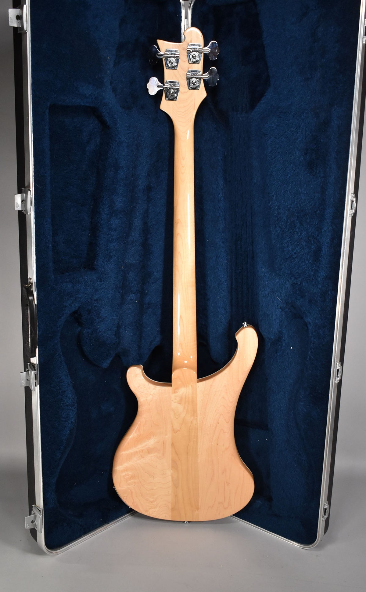 The bass is shown from behind, in its open hard case, revealing the natural maple finish of the body and neck.