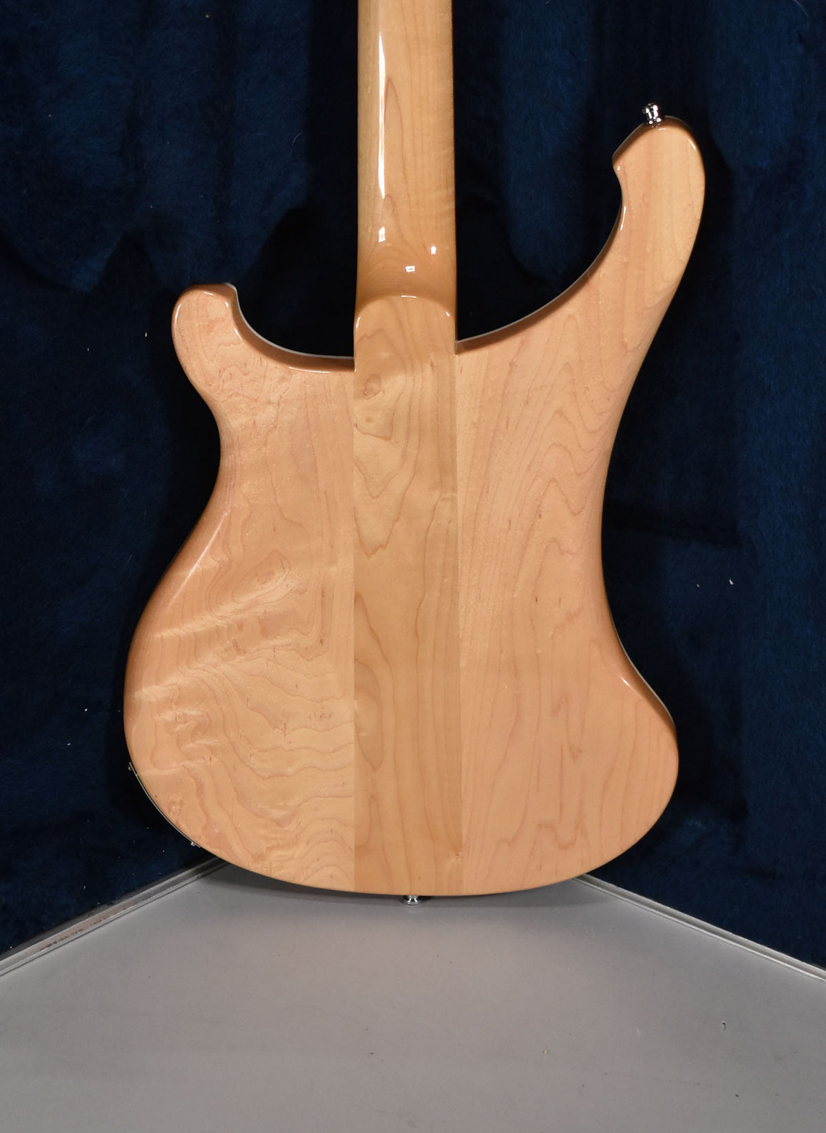The back of a light maple bass with a glossy finish, showing the neck-through construction and a strap button on the upper horn.
