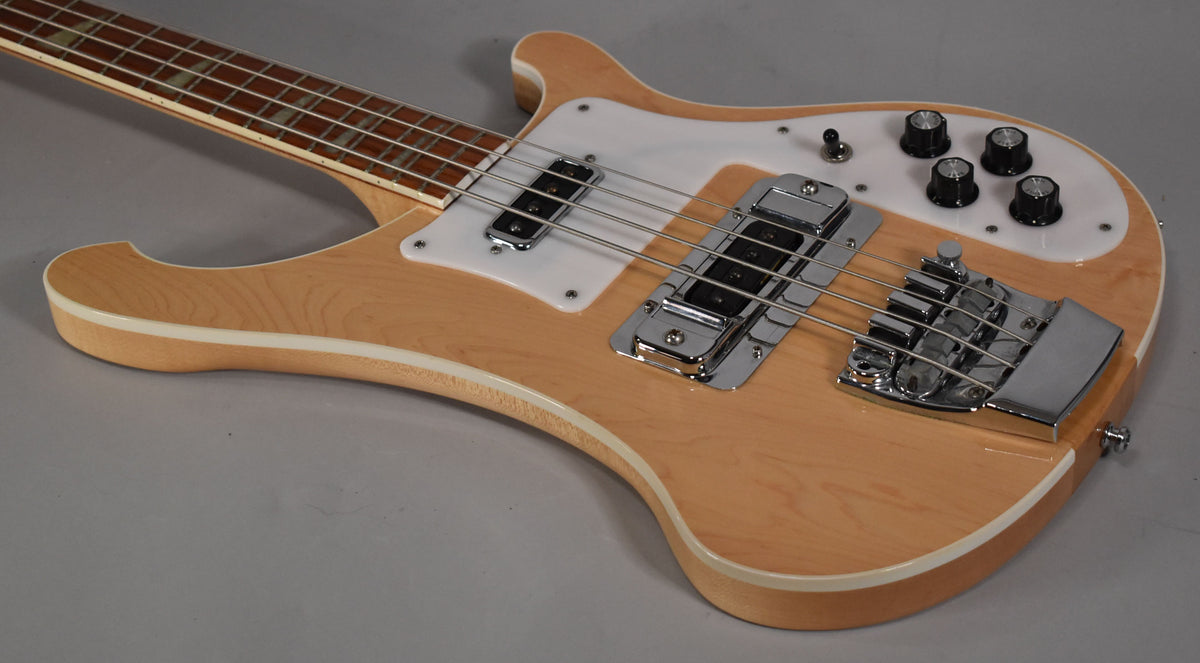 The natural maple bass body, with white binding and pickguard, is angled to show the chrome bridge and control knobs.