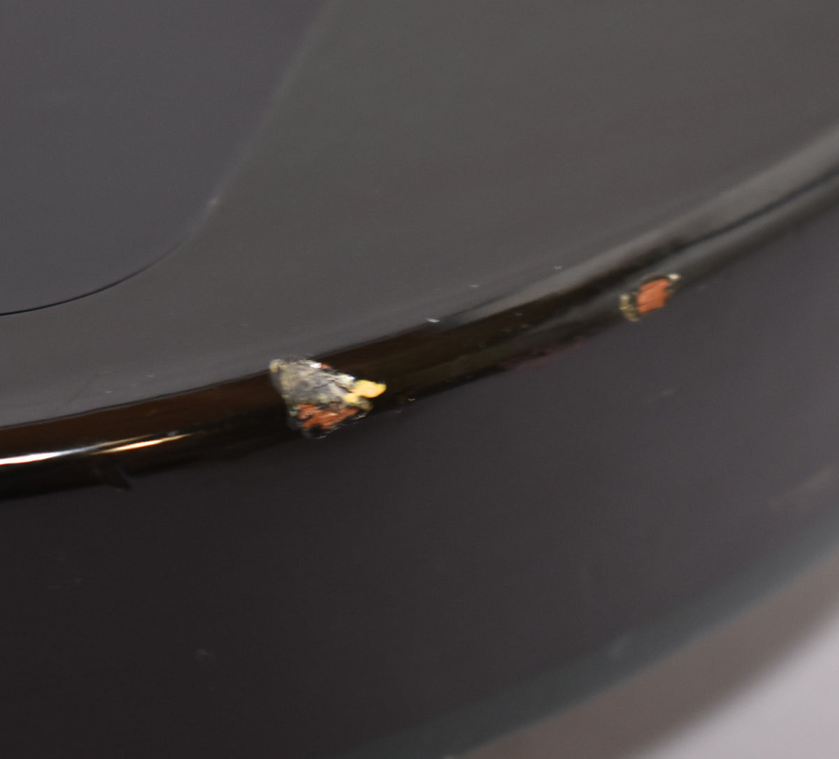 Close-up of the guitar's emerald green body, showing two chips in the finish along the edge, revealing lighter wood underneath.