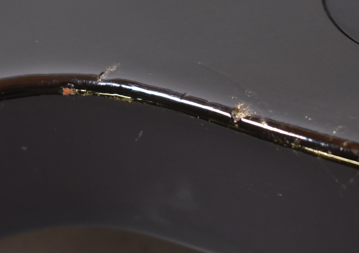 Close-up of the guitar's dark green body binding, showing several chips and wear spots along its edge, revealing lighter wood beneath.