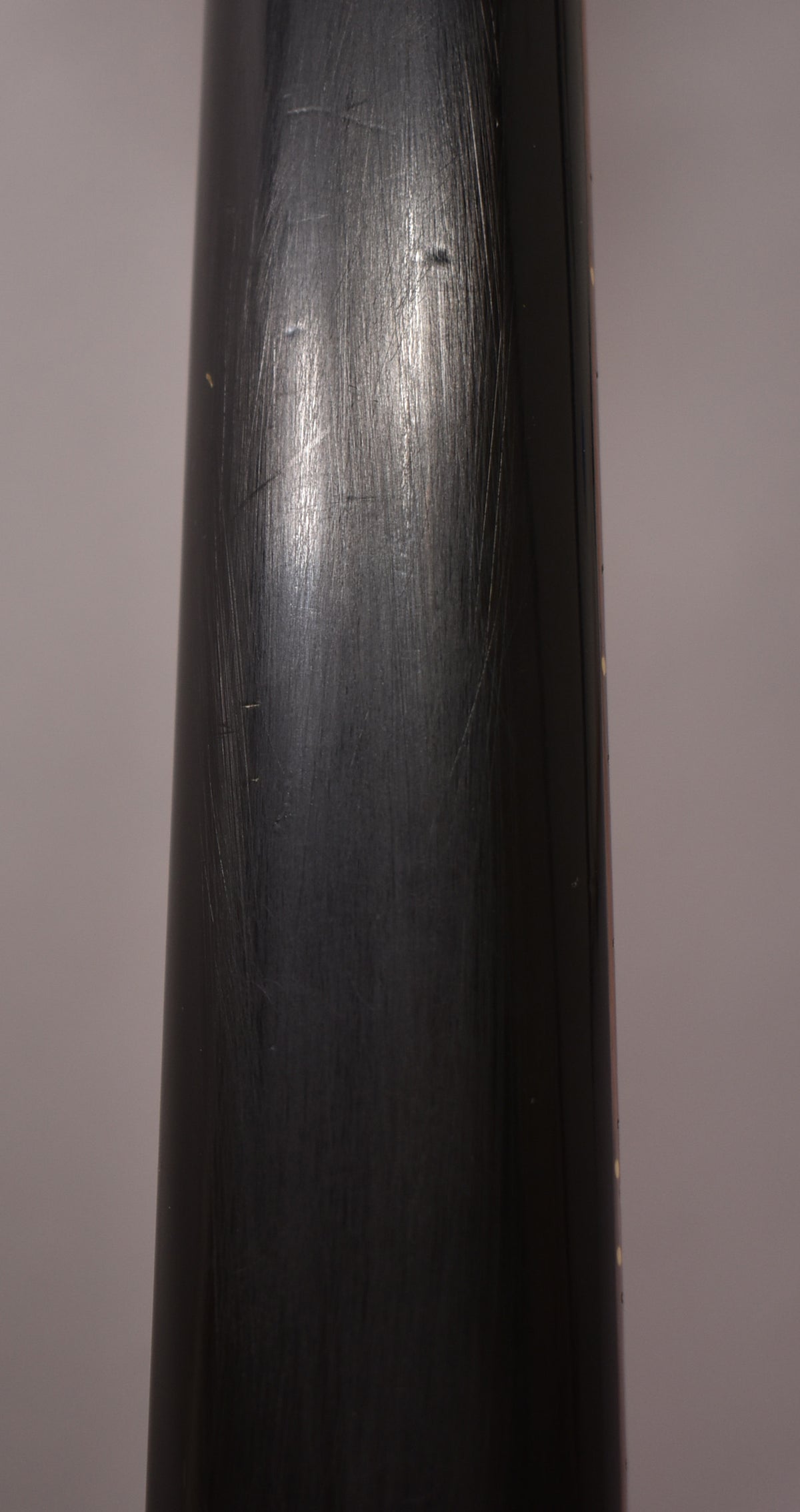 Close-up of the guitar's dark green neck, showing numerous light scratches and a few small dings on the satin finish.