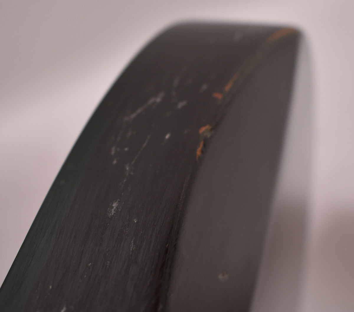 Close-up of the guitar's dark green body edge, showing several chips and scratches revealing the lighter wood underneath.