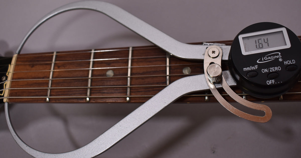 A digital caliper measures the guitar's nut width at 1.64 inches, showing the dark rosewood fretboard and frets.