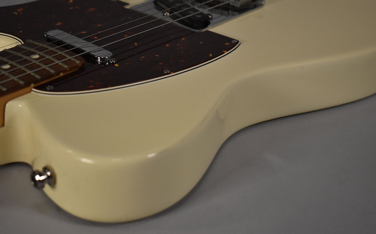 Close-up of the Telecaster's lower bout, showing the Olympic White finish, tortoiseshell pickguard, and chrome neck pickup.