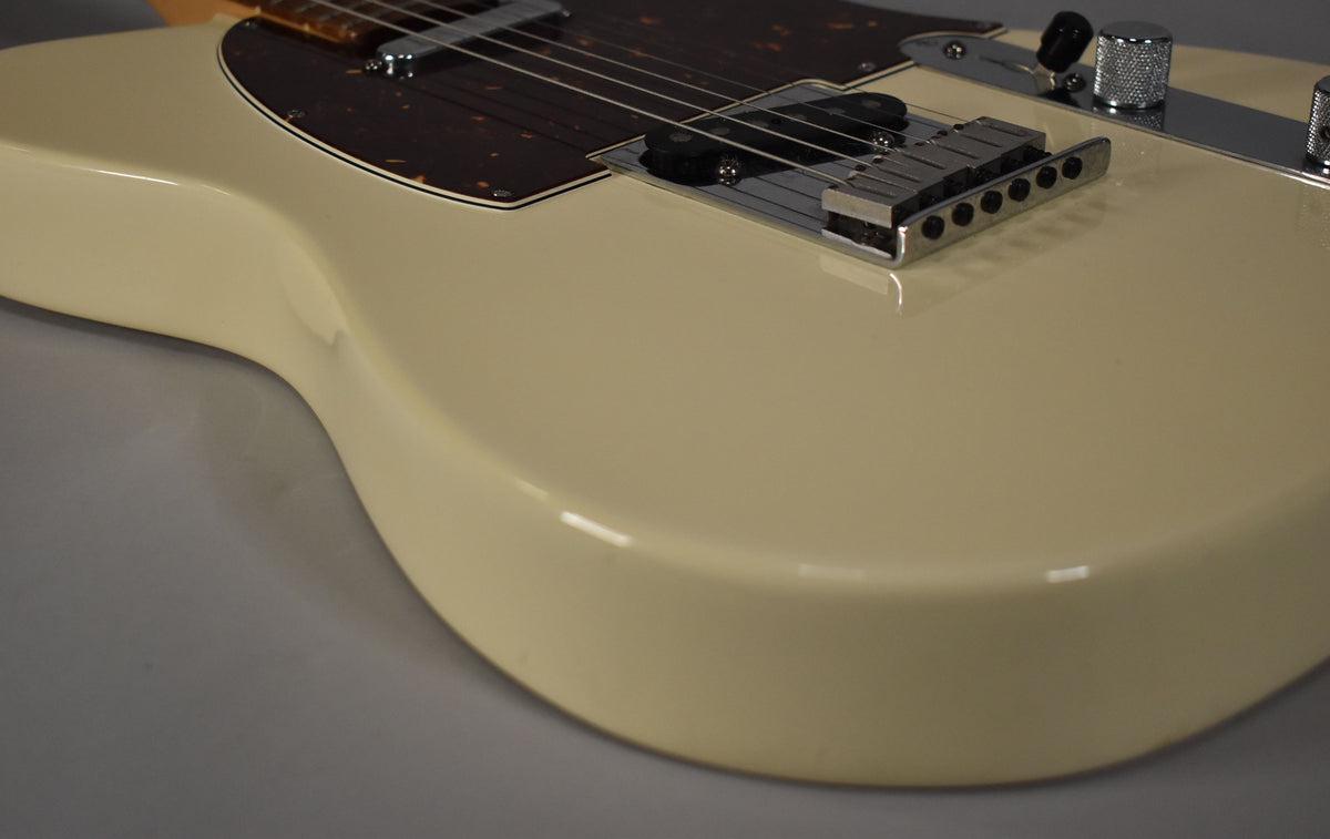 Close-up of the guitar body, showing the Olympic White finish, tortoiseshell pickguard, chrome bridge, and control plate with knurled knobs.