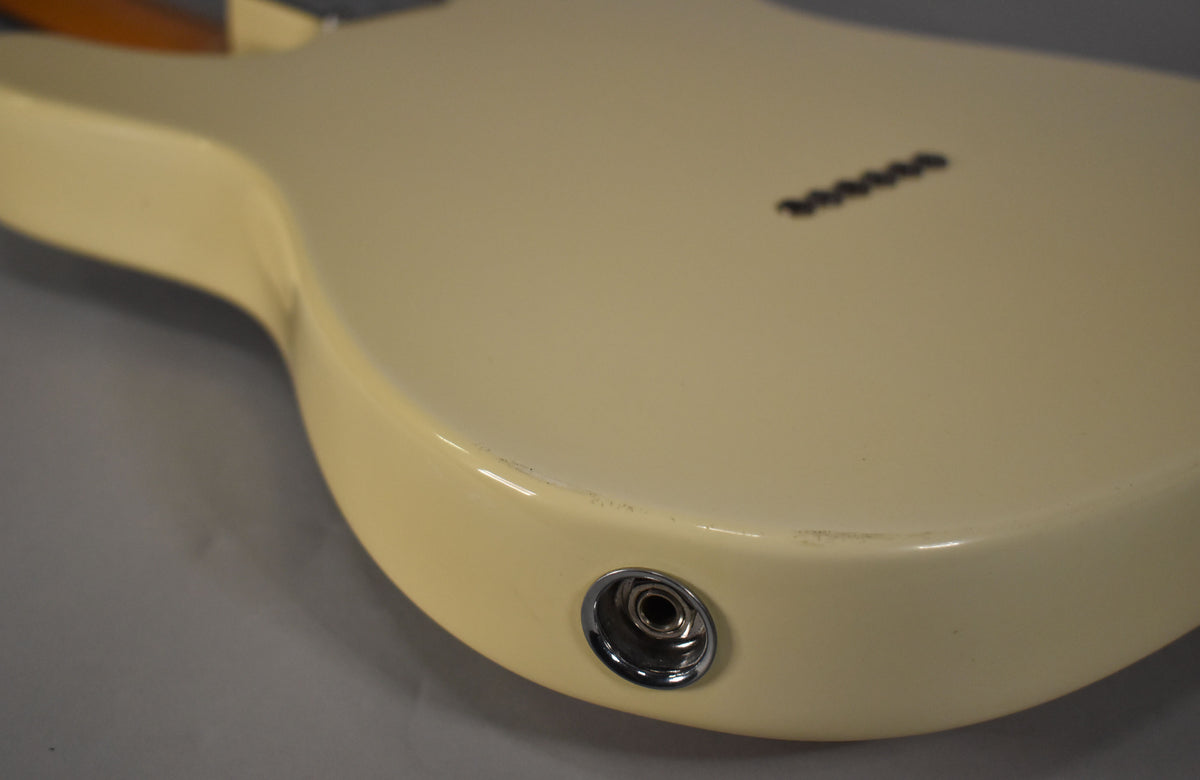 Close-up of the guitar's lower body, showing the Olympic White finish, chrome output jack, and string-through-body ferrules.