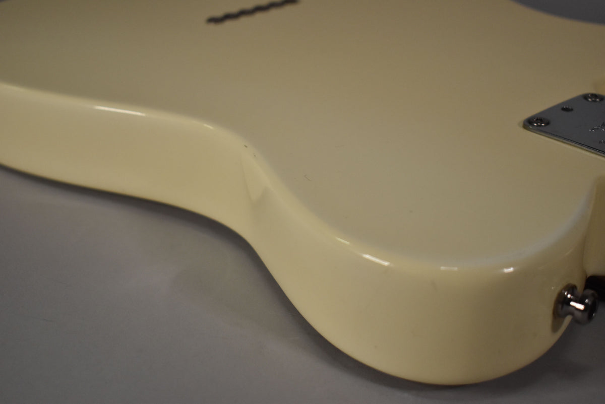 Close-up of the lower bout of an Olympic White Telecaster, showing the output jack and a few small dings.