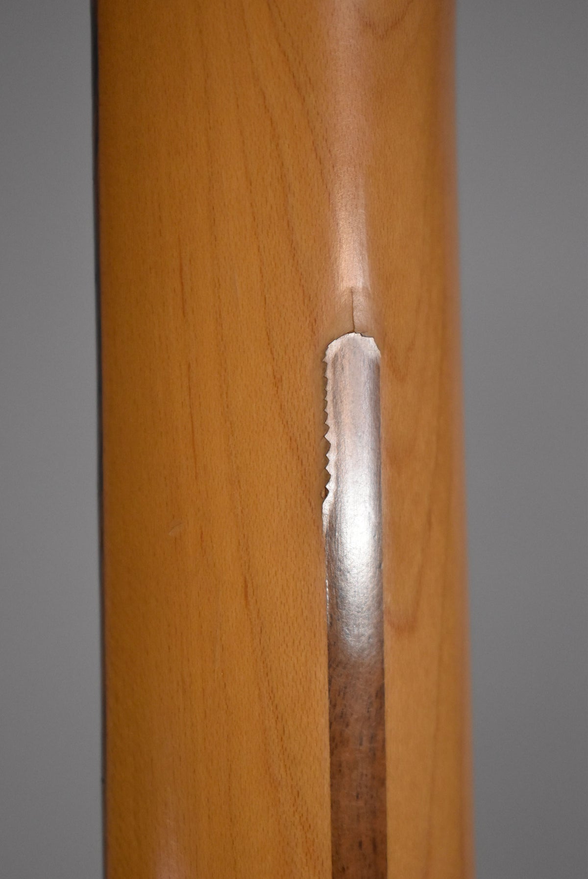 Close-up of the guitar neck's back, showing a long, deep chip in the finish revealing lighter wood, with a jagged edge.