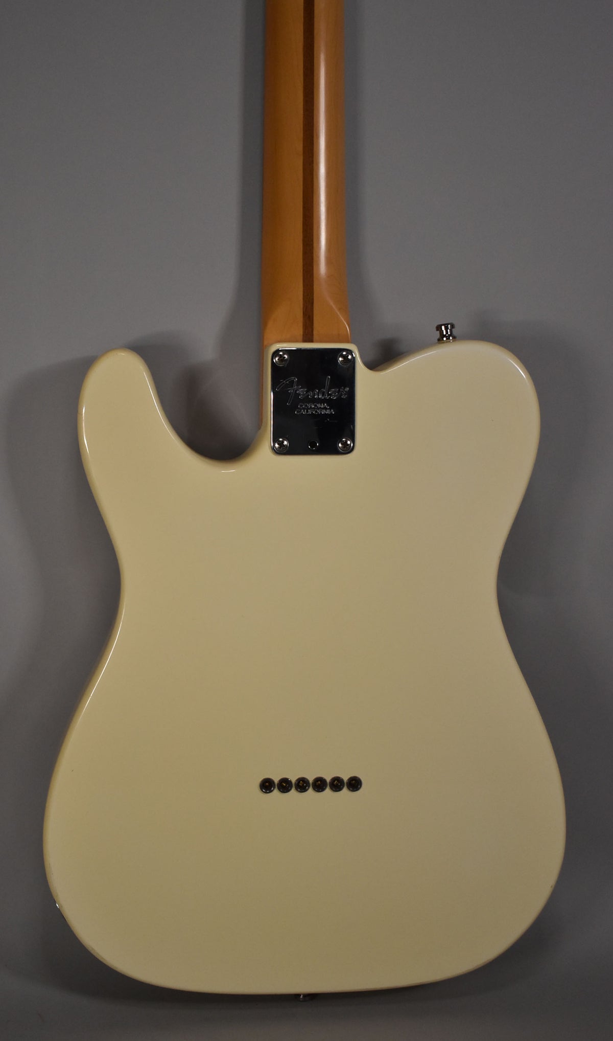 The back of an Olympic White Telecaster, showing the neck plate, string-through-body ferrules, and a light-colored maple neck.
