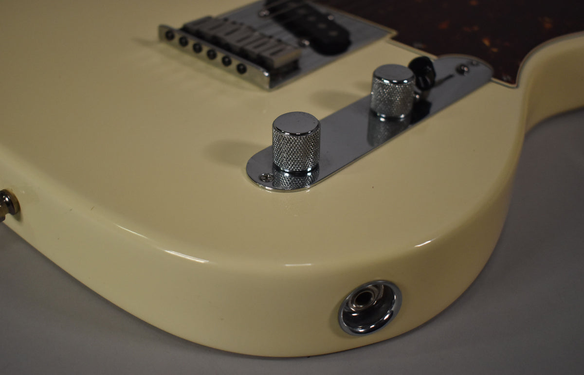 Close-up of the guitar's lower body, showing the Olympic White finish, chrome control plate with two knurled knobs, and output jack.