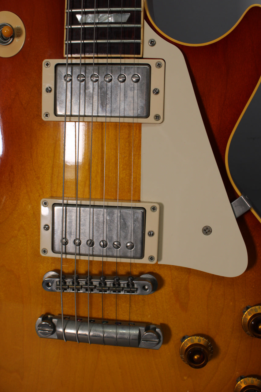Close-up of the guitar's body, showing the cherry sunburst finish, two humbucker pickups, cream pickguard, and bridge hardware.