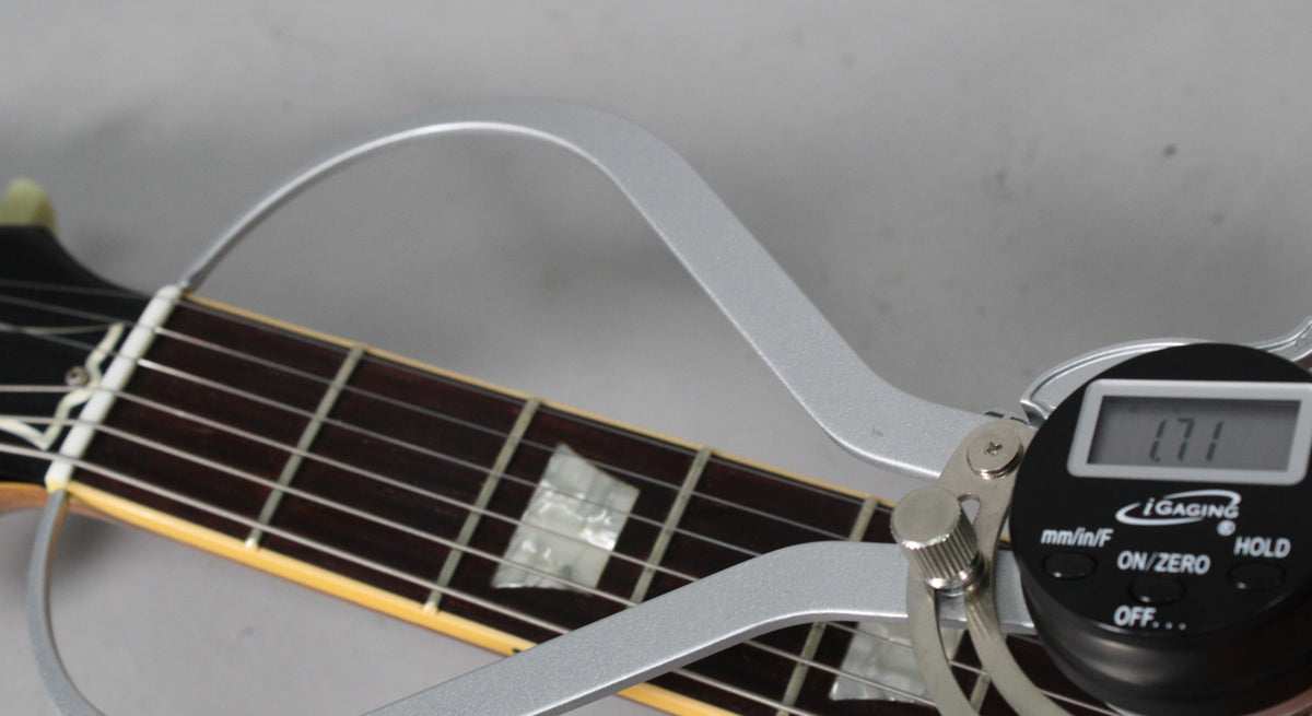 Close-up of the guitar's dark fretboard with trapezoid inlays, measured by a silver digital caliper showing "1.71".