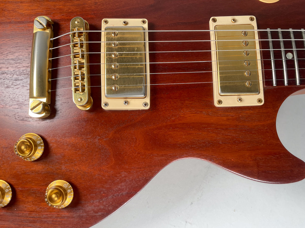 Close-up of the guitar's body, showing the natural wood grain, gold hardware, two humbuckers, bridge, tailpiece, and four control knobs.