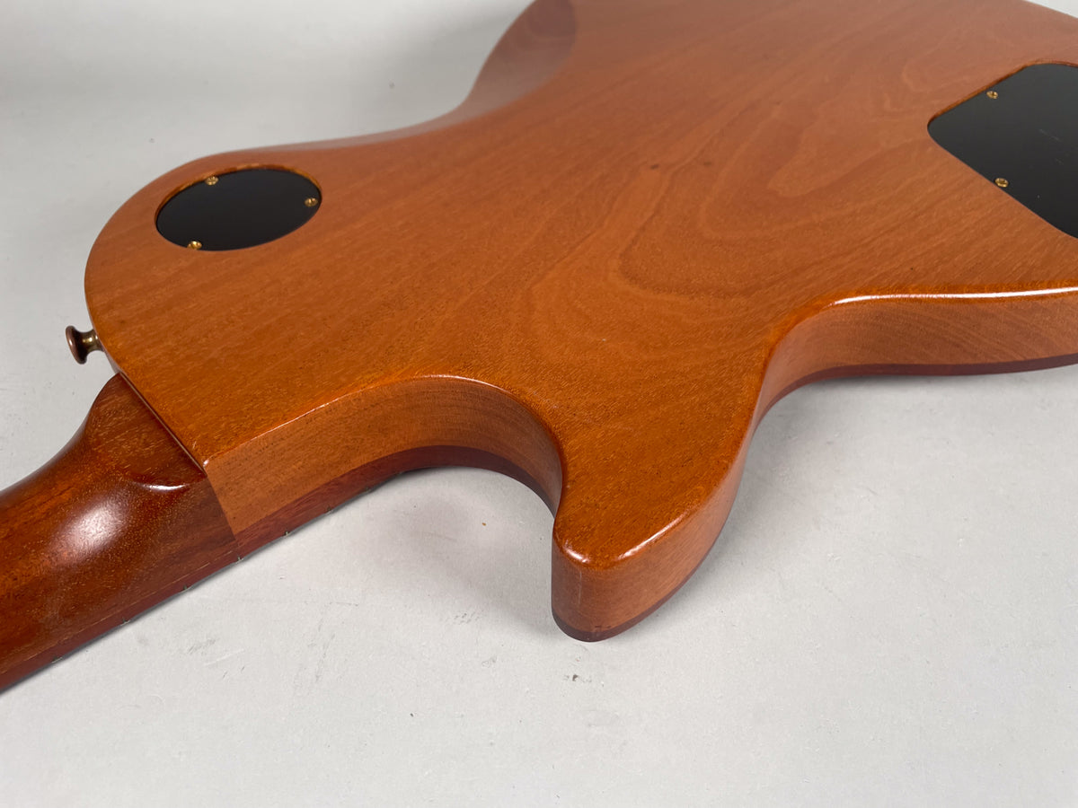 Rear view of the guitar's natural finish body and neck joint, showing the control cavity cover and a strap button.