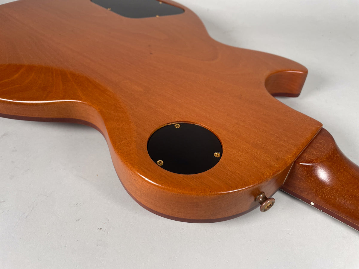The back of the guitar's body and neck joint, showing the natural wood finish, control cavity cover, and strap button.