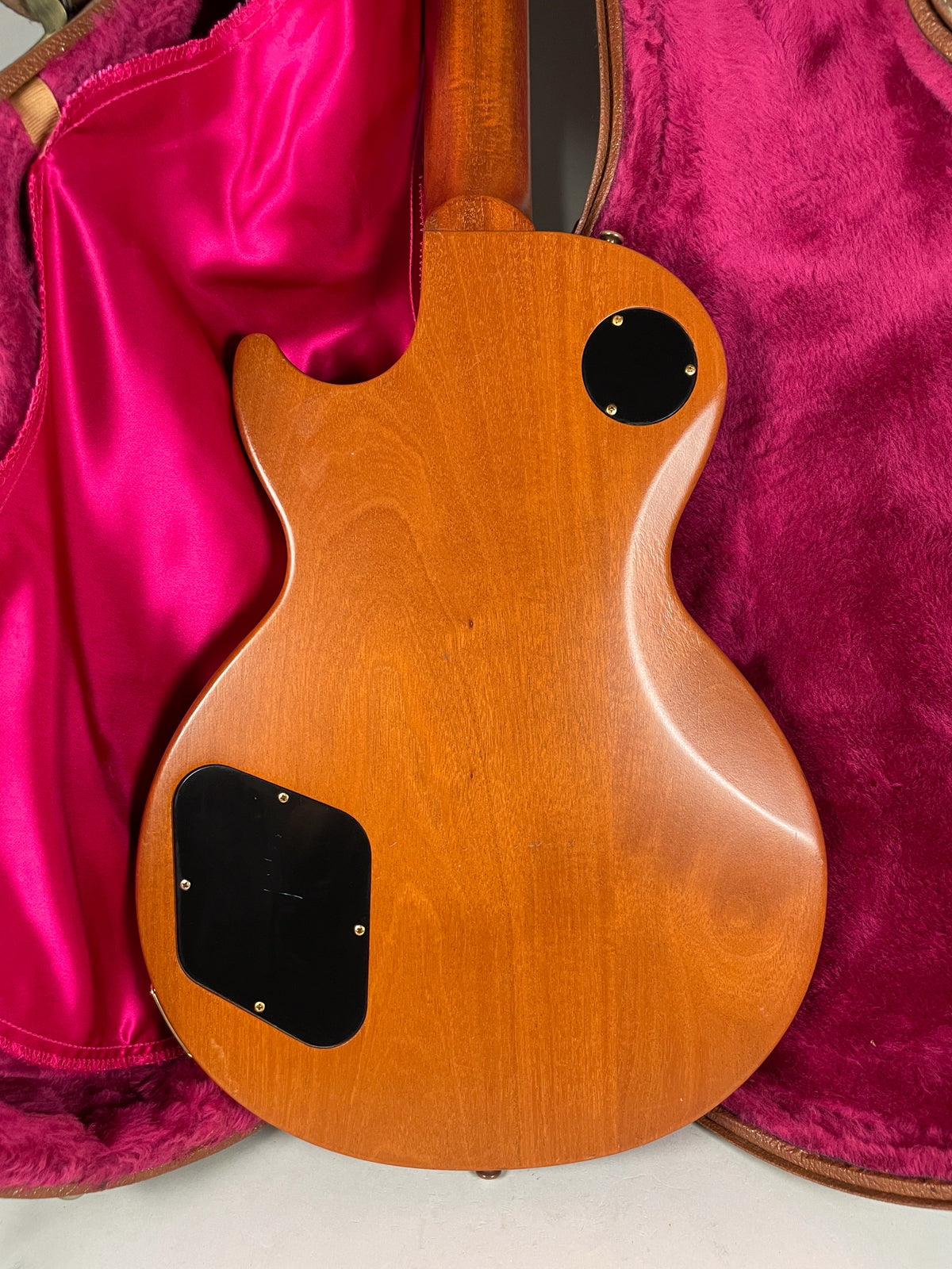 The guitar's natural wood back, with a satin finish, shows two black control cavity covers and a few minor dings.