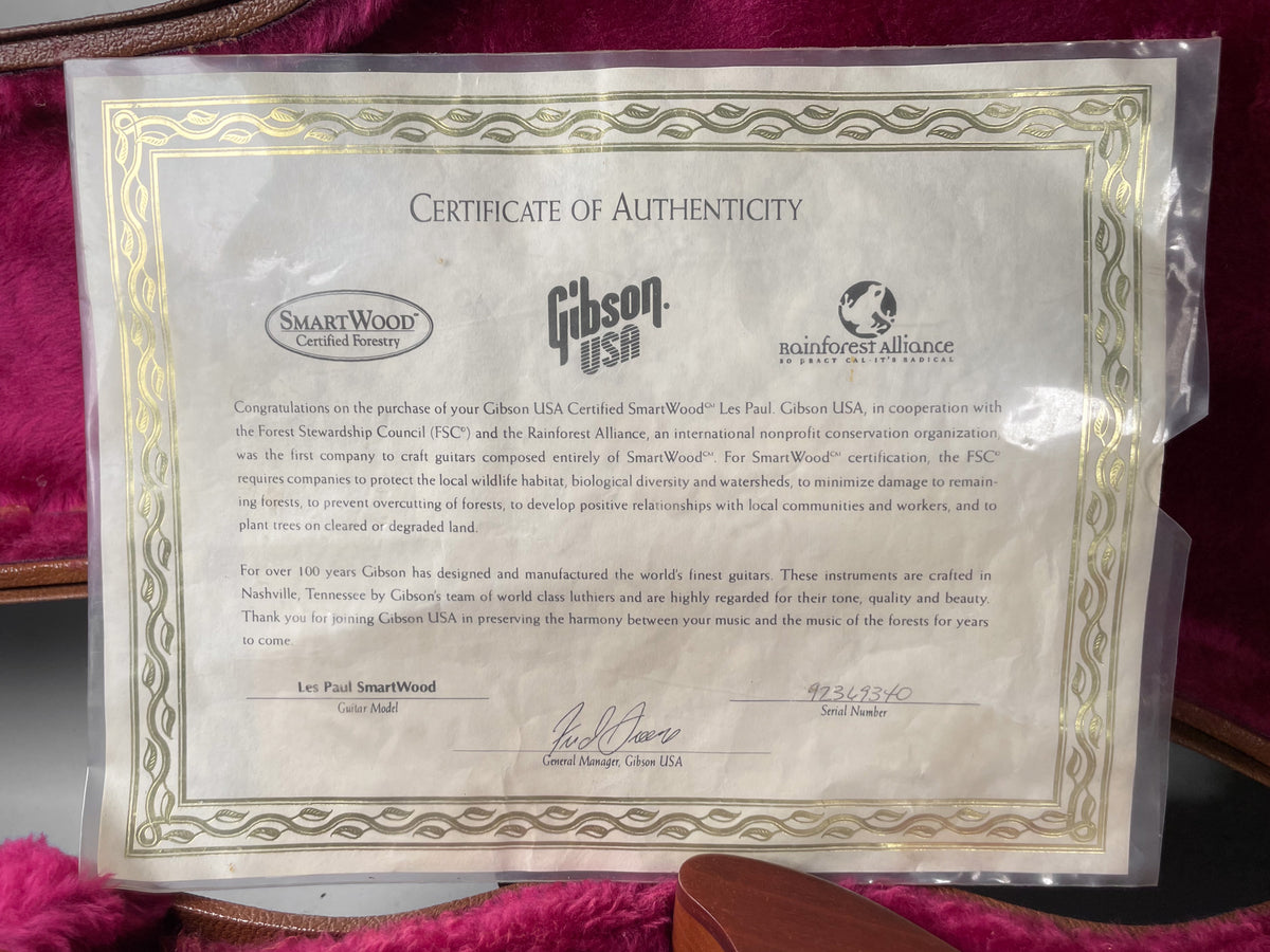 A close-up of the guitar's Certificate of Authenticity, a cream-colored document with gold borders, inside a plastic sleeve.