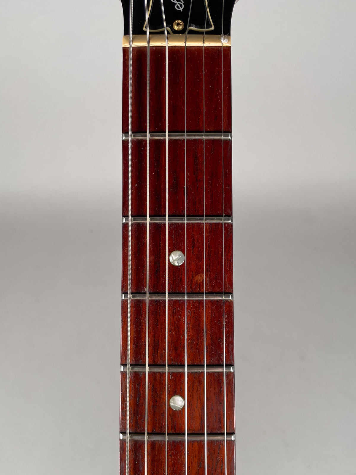 Close-up of the guitar's dark reddish-brown fretboard with silver frets and dot inlays, showing light wear and a small scuff.