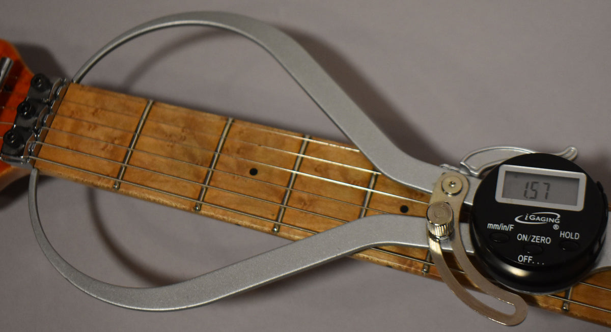 Close-up of the guitar's maple fretboard with a digital caliper measuring the fret height at 1.57mm.