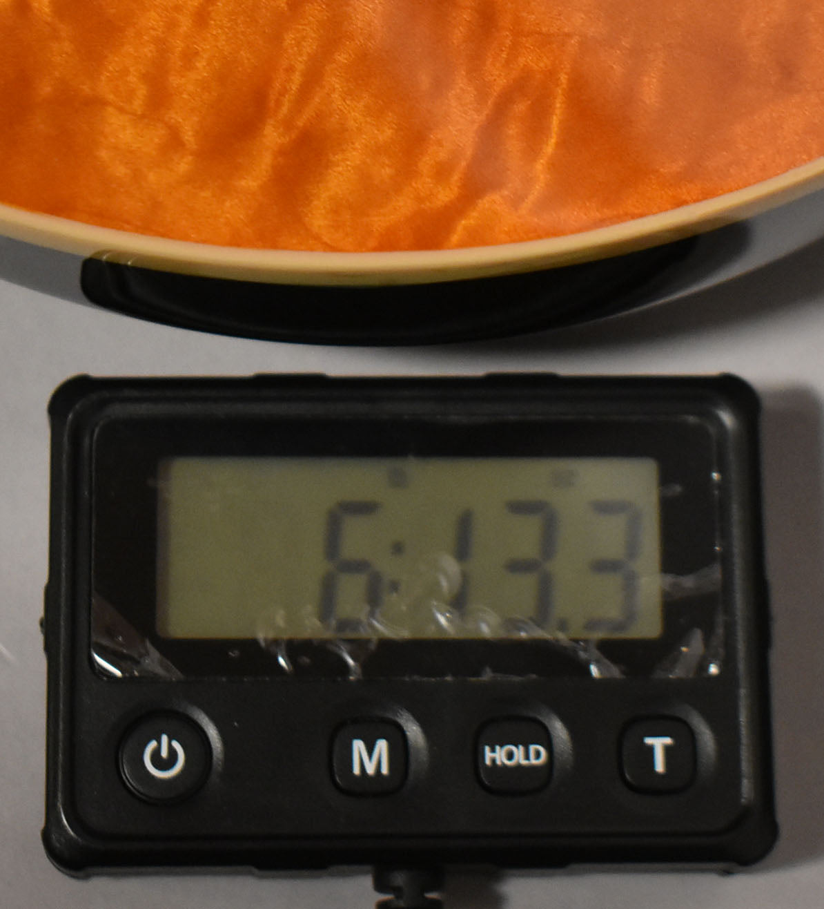 Close-up of the guitar's orange flamed maple top and cream binding, with a digital scale displaying "6:13.3" in the foreground.
