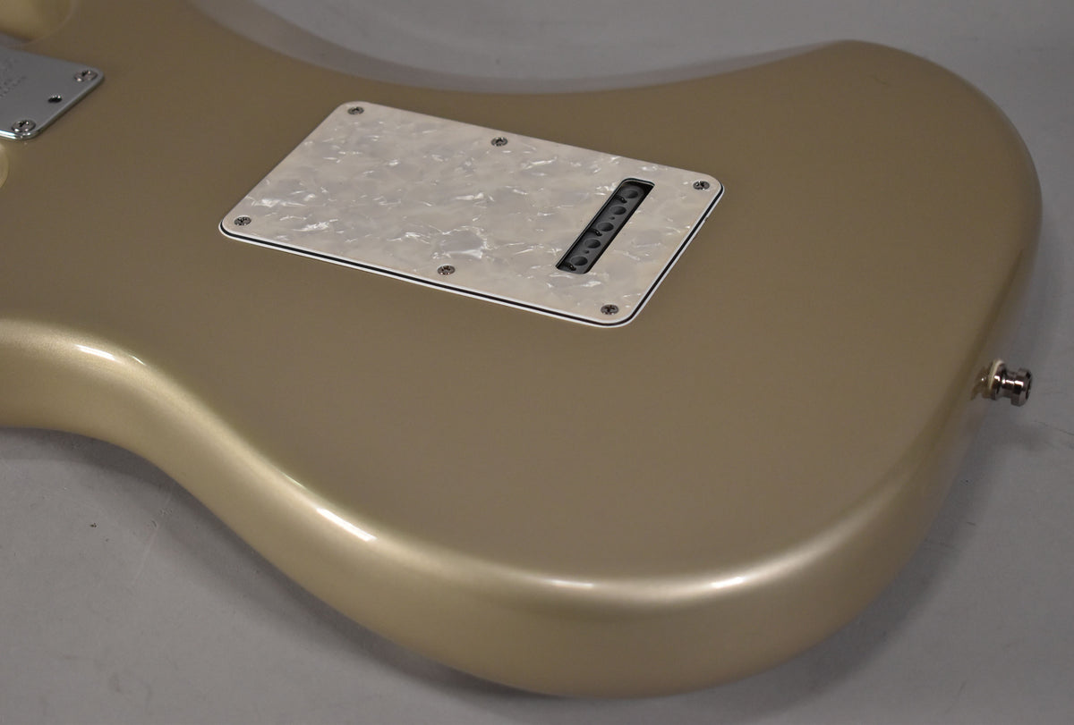 The back of a Shoreline Gold Stratocaster body with a pearloid tremolo cover and a strap button.