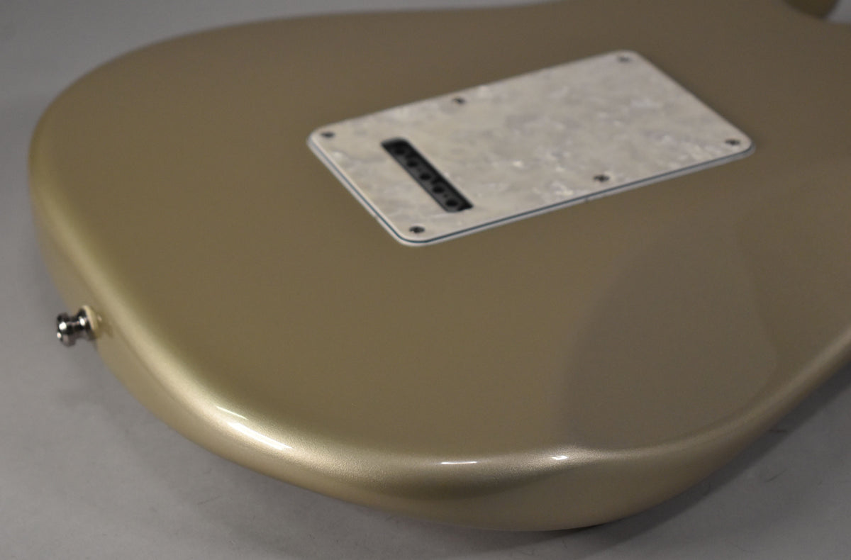 Close-up of a Shoreline Gold guitar body with a pearloid tremolo cover and a chrome strap button.