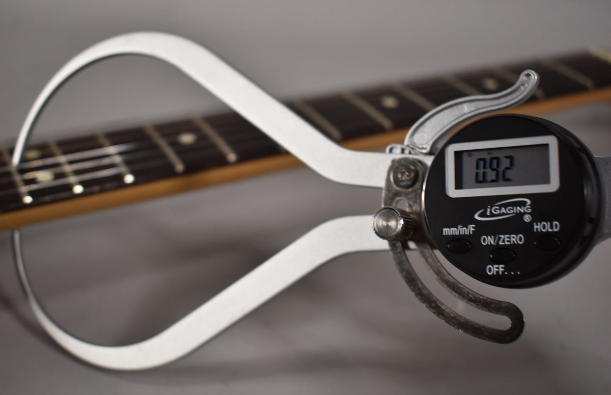 A digital caliper measures the fret height at 0.92mm on the dark rosewood fretboard with cream dot inlays.