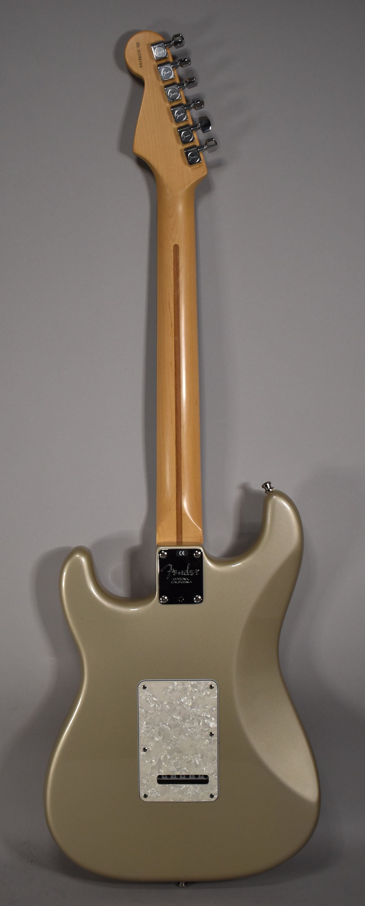 Back of a Shoreline Gold Fender Stratocaster with a maple neck, chrome tuners, and a pearloid tremolo cover.