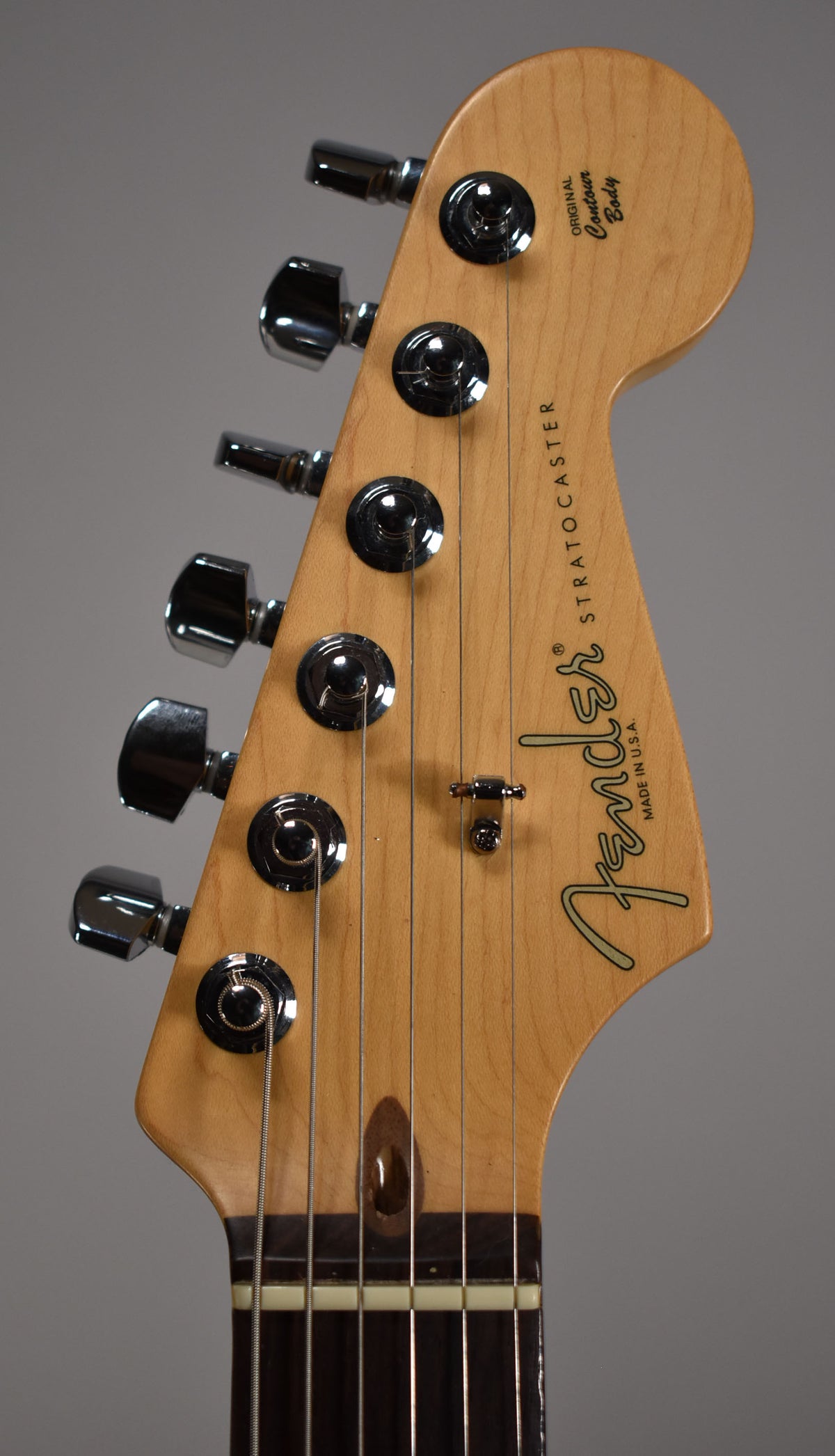 Close-up of the light-colored maple headstock, showing six chrome tuners, a string tree, and a dark brown truss rod access.