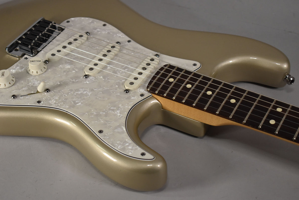 Close-up of a Shoreline Gold Stratocaster body with a pearloid pickguard, three single-coil pickups, and part of the fretboard.