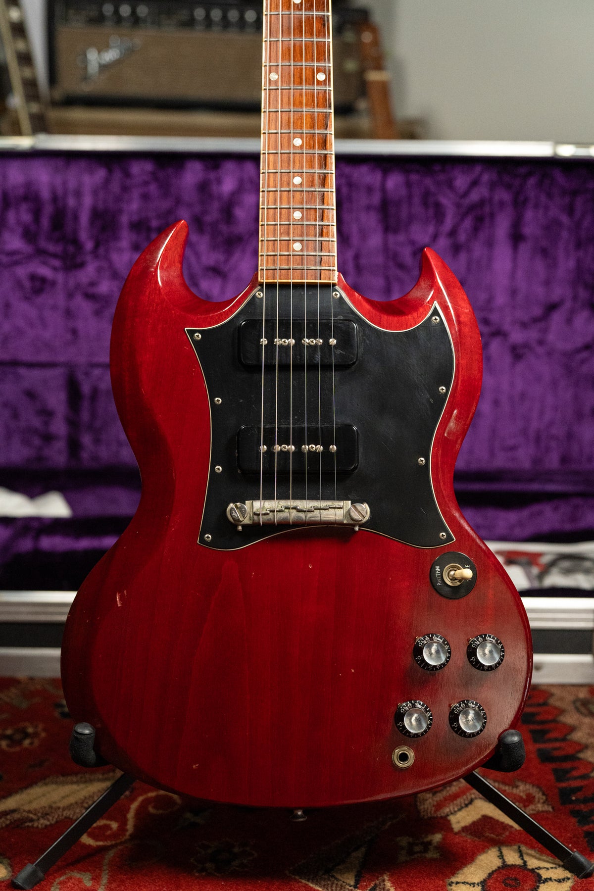 A full-frame shot of a cherry red SG with a black pickguard, two P90 pickups, and four black control knobs.