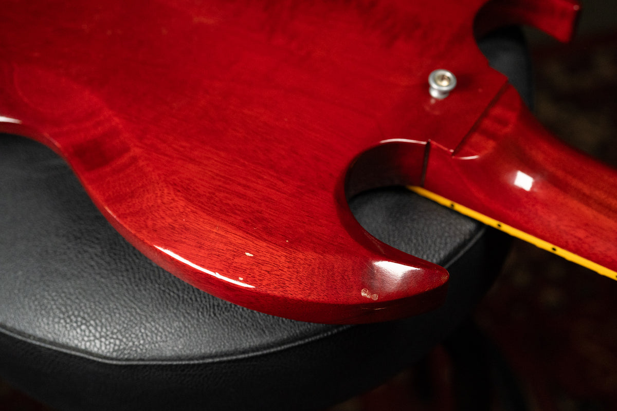 Close-up of the deep cherry red SG body, showing a few small chips on the lower horn and a strap button near the neck joint.