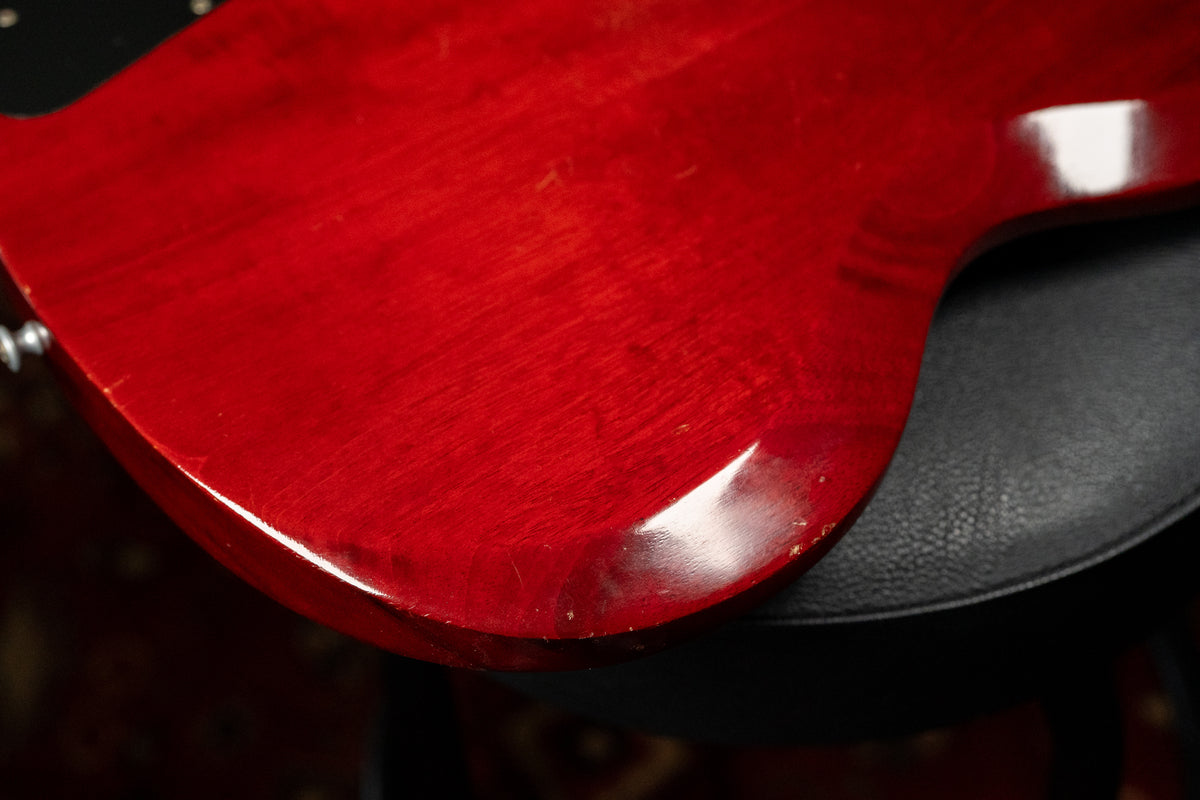 Close-up of the lower bout of a cherry red SG, showing finish wear, scratches, and dings along the edge and on the body.