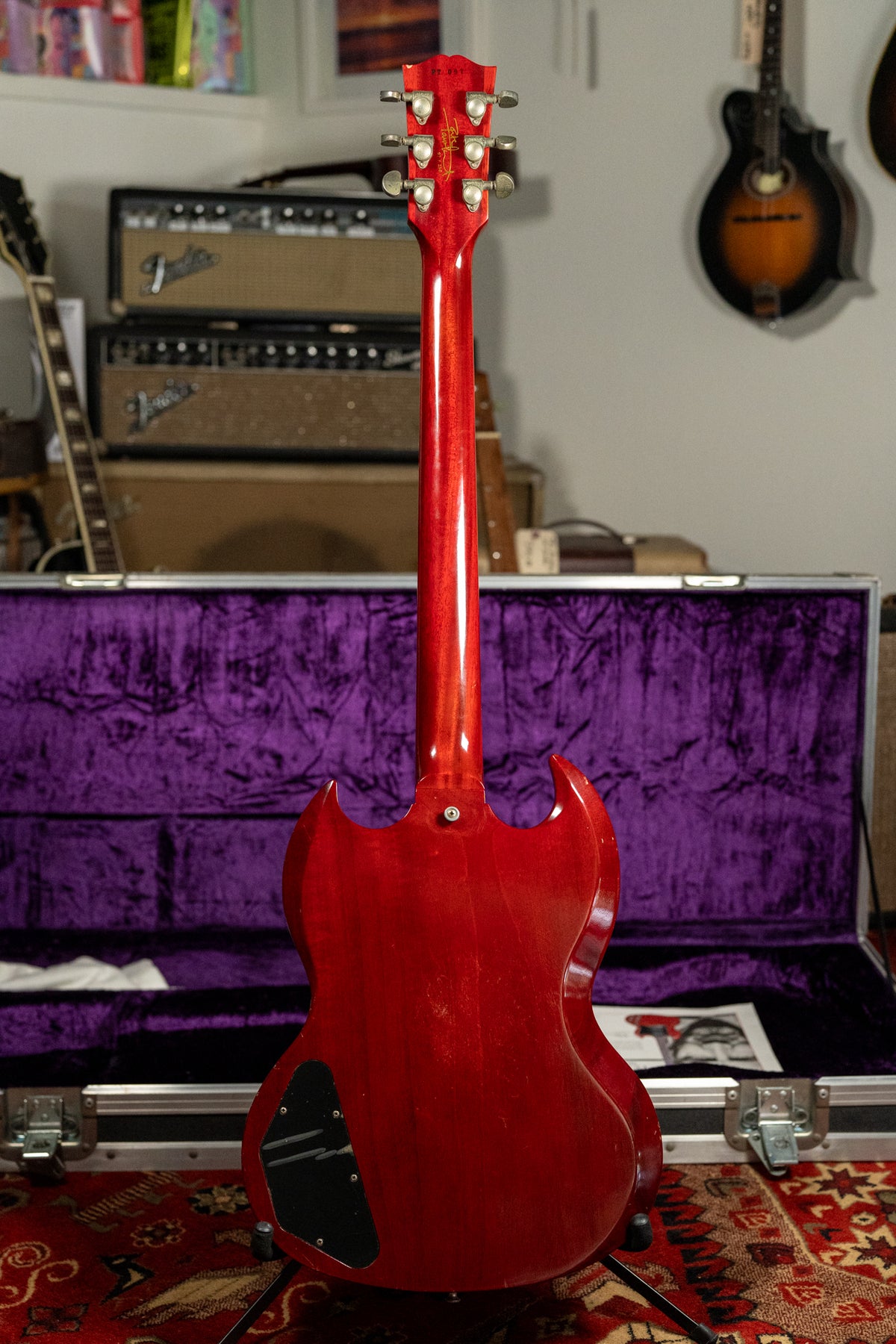 The back of a cherry red SG with a glossy finish, showing the neck, headstock with six tuners, and control cavity cover.
