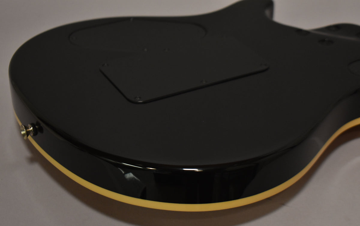 The guitar's glossy black back is angled, revealing a cream binding, two control cavity covers, and a chrome strap button.