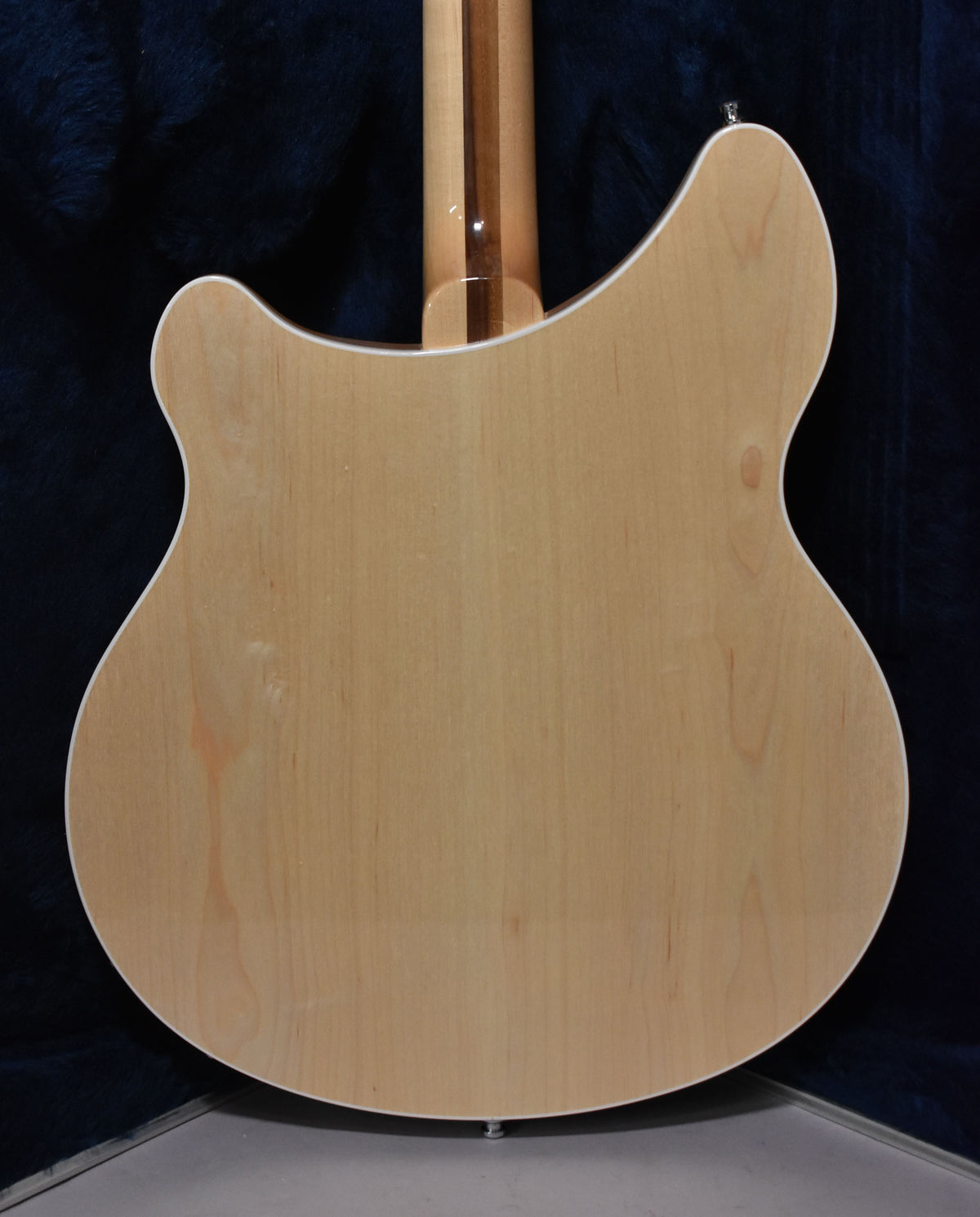 The guitar's back, a light maple with a glossy finish, shows a few minor scuffs and a dark-striped neck.