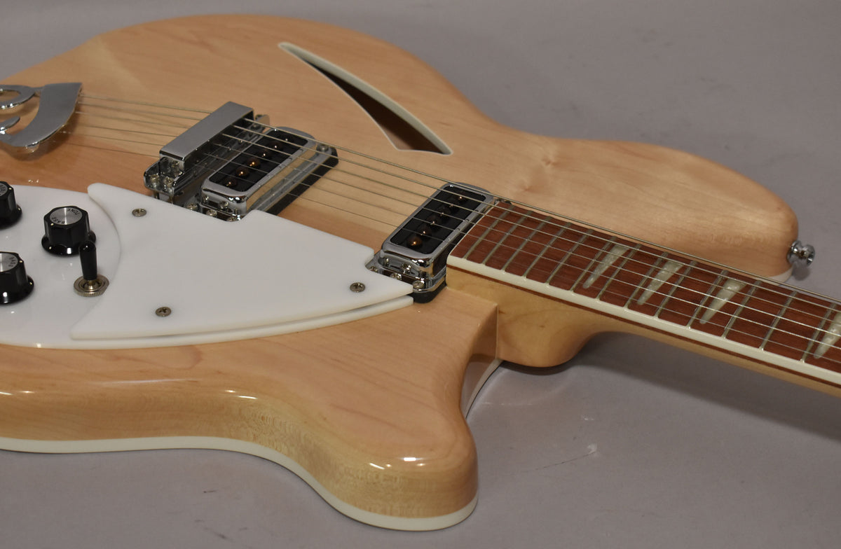 The Mapleglo hollow-body guitar, angled from the lower bout, shows its white pickguard, chrome pickups, and f-hole.
