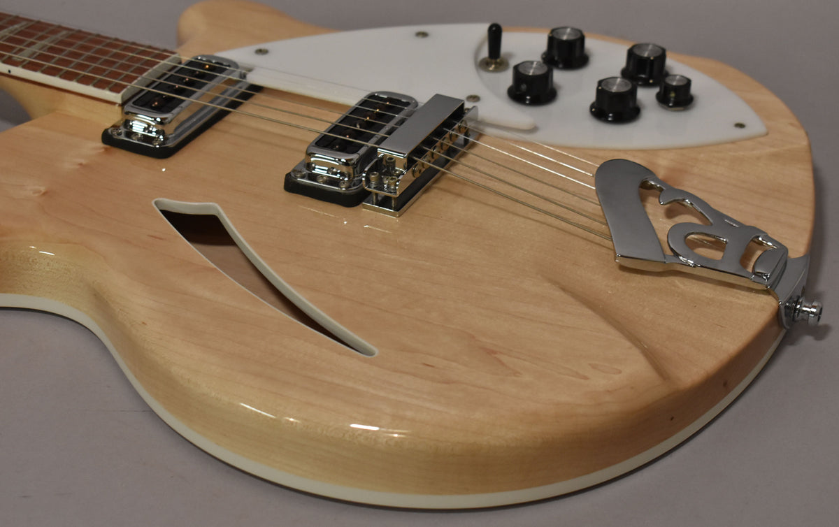 Close-up of the guitar's lower body, showing the light maple finish, f-hole, chrome hardware, and white pickguard with black knobs.