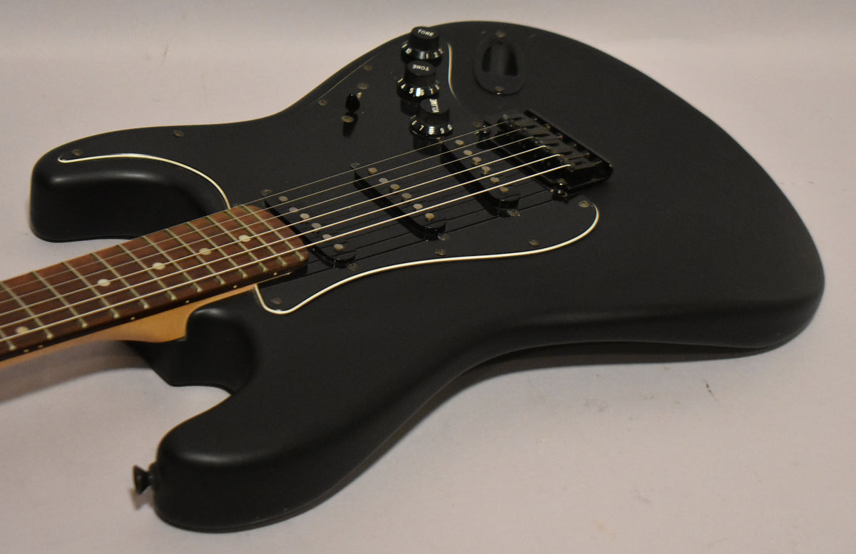 The black satin Stratocaster body is angled from the lower left, showing the neck, black pickguard, three single-coil pickups, and controls.