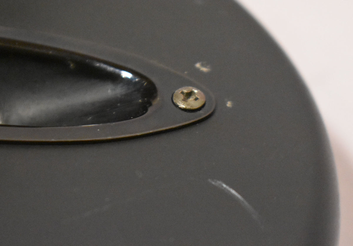 Close-up of the black satin body, showing the input jack plate with a single screw, surrounded by light scratches and dings.
