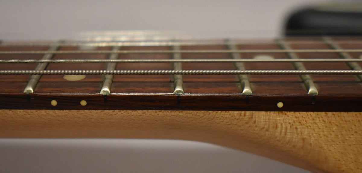 Close-up of the guitar's fretboard and lower neck, showing light wear on the dark wood, frets, and side dot markers.