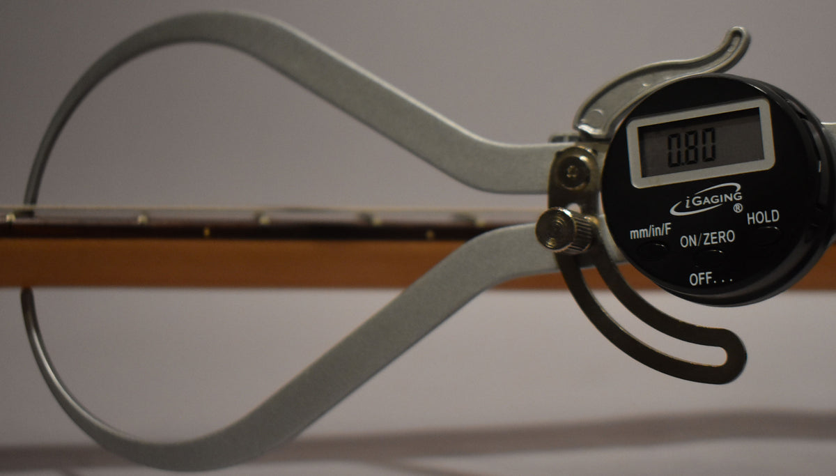 A digital caliper measures the string height at 0.80mm above the fretboard, visible from the side.