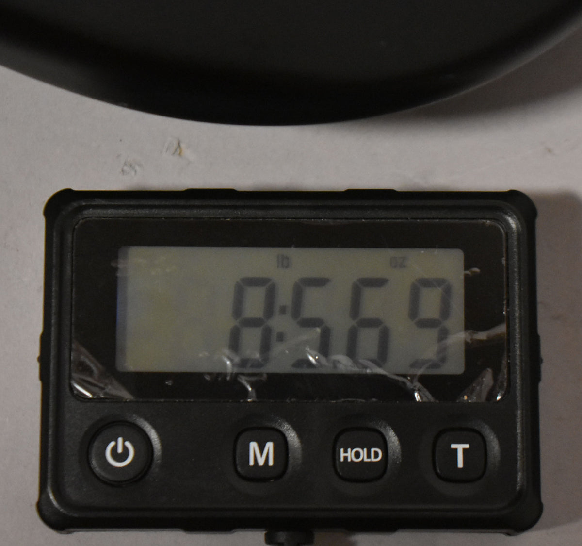 A close-up of a digital scale displaying "8.569 lb" with a slightly scratched screen protector, showing the guitar's weight.
