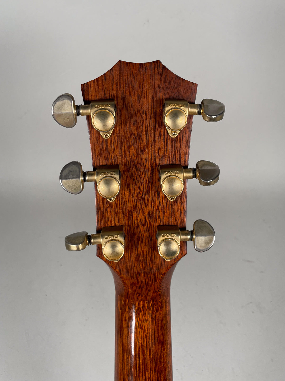 Rear view of the guitar's headstock and upper neck, showing six gold-colored tuners with light wear on the metal.