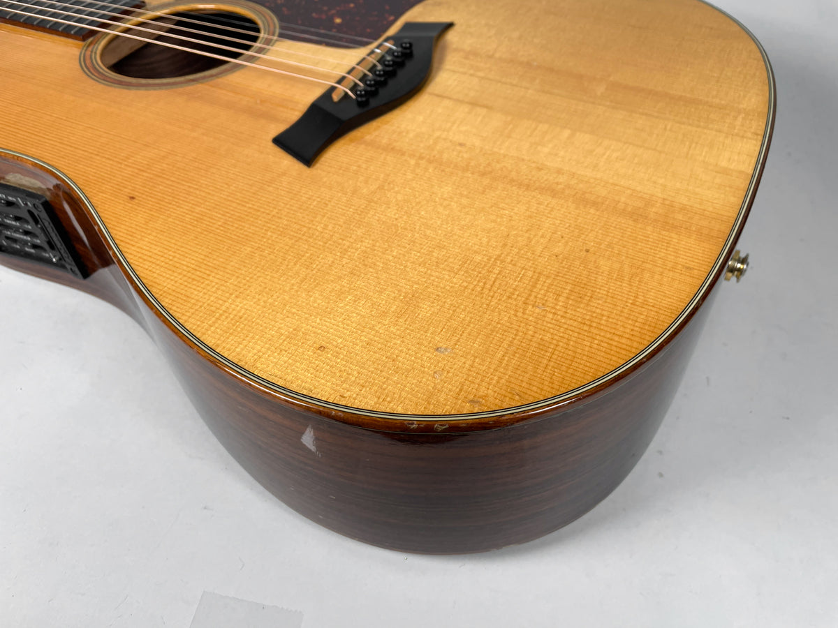 Upper bout of the natural finish acoustic guitar, showing the dark wood sides, light top with fine grain, and some minor dings.