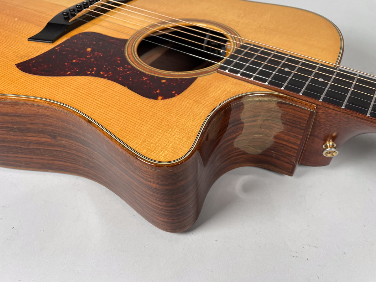 Upper body of a natural finish acoustic guitar, showing a dark tortoiseshell pickguard, cutaway, and strap button.