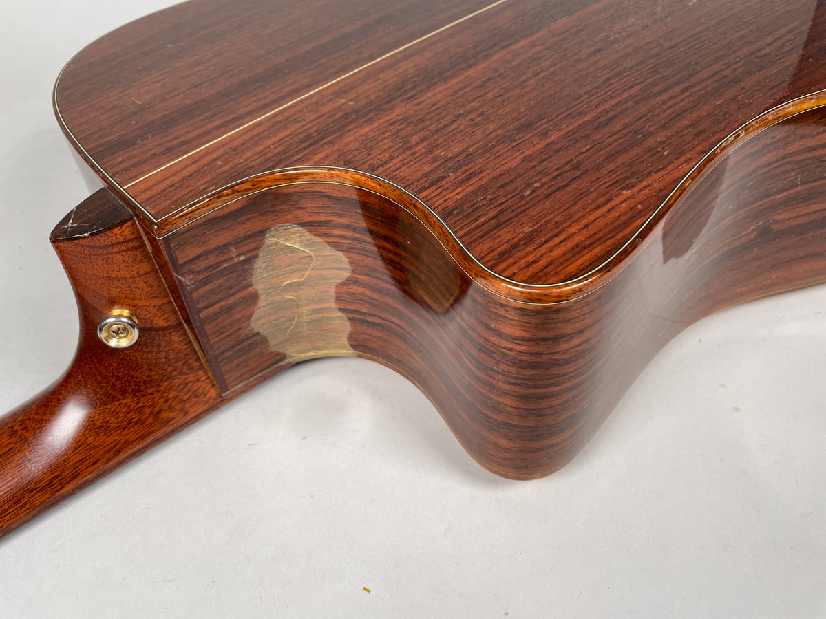Close-up of the guitar's lower bout and neck heel, showing a large area of finish wear on the dark wood body.